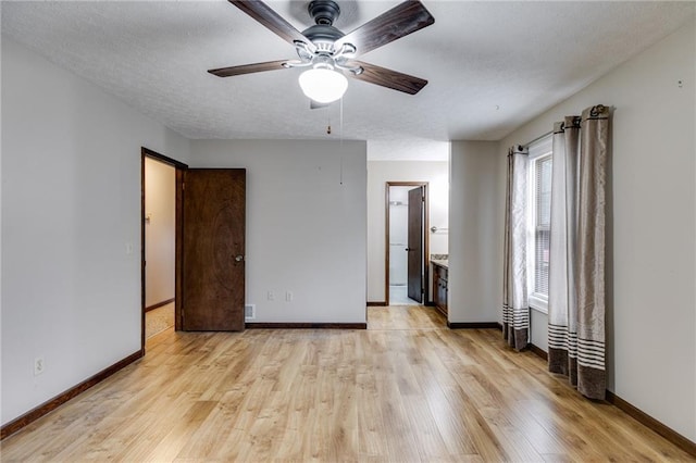 unfurnished bedroom featuring ceiling fan, ensuite bath, light hardwood / wood-style flooring, and a textured ceiling