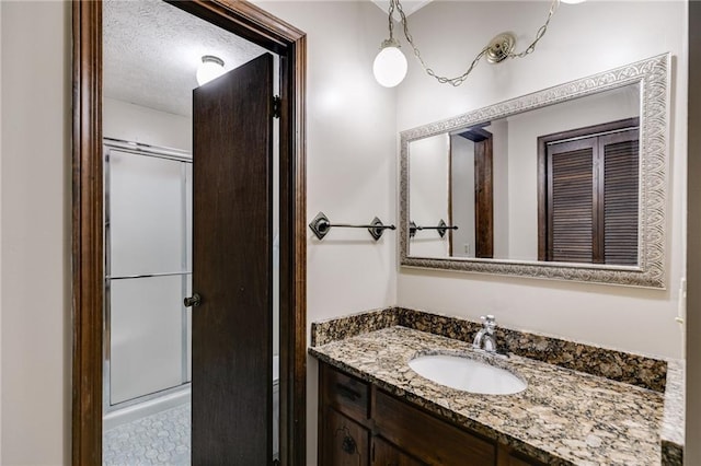 bathroom featuring vanity, an enclosed shower, and a textured ceiling