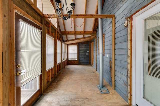 unfurnished sunroom featuring vaulted ceiling with beams, a notable chandelier, and a healthy amount of sunlight