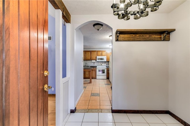 corridor with light tile patterned floors and a textured ceiling