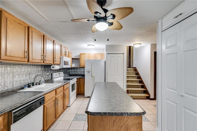 kitchen with sink, a center island, light tile patterned floors, white appliances, and backsplash