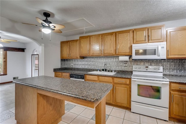 kitchen with tasteful backsplash, sink, white appliances, and a center island