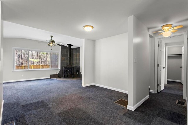 1833 Lost Mountain Rd, Powder Springs, GA 30127 - unfurnished living room featuring visible vents, baseboards, ceiling fan, a wood stove, and dark colored carpet