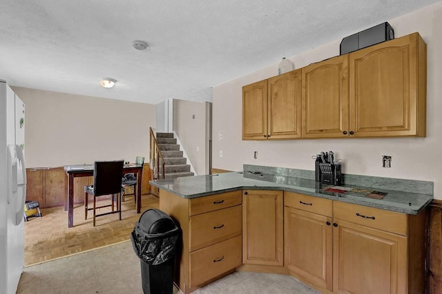 504 Rock Meadow Dr, Stone Mountain, GA 30088 - kitchen featuring white refrigerator with ice dispenser, a peninsula, a textured ceiling, and dark stone countertops