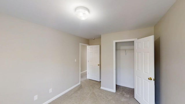 unfurnished bedroom with light carpet, baseboards, and a closet