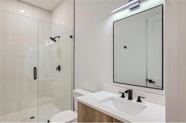 bathroom featuring vanity, a shower with shower door, and toilet