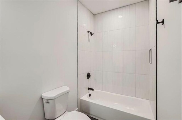 bathroom with tiled shower / bath combo and toilet