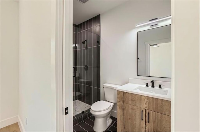 bathroom featuring tiled shower, tile patterned floors, vanity, and toilet