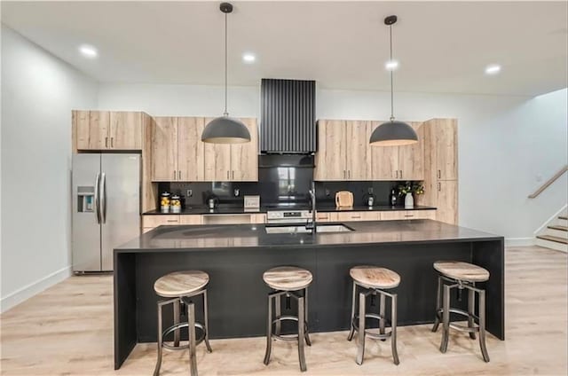 kitchen with stainless steel fridge with ice dispenser, a center island with sink, and hanging light fixtures