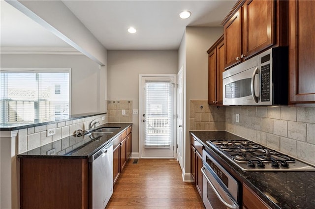 kitchen featuring dark stone counters, appliances with stainless steel finishes, a sink, and a healthy amount of sunlight