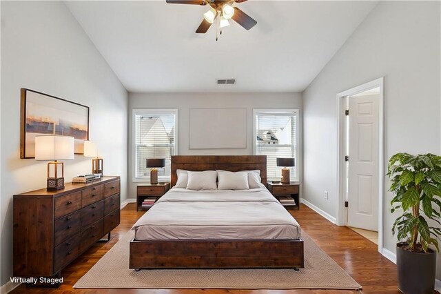 bedroom featuring visible vents, vaulted ceiling, baseboards, and wood finished floors