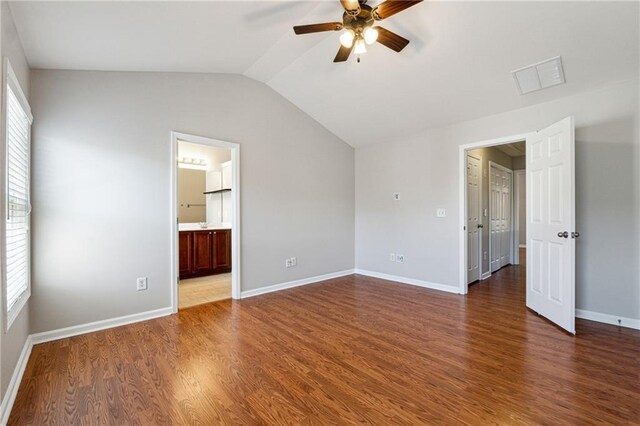 unfurnished bedroom with multiple windows, baseboards, vaulted ceiling, and wood finished floors