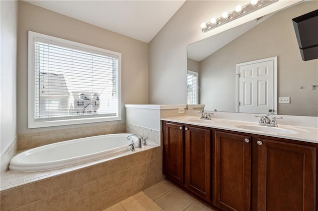 full bath with a garden tub, tile patterned floors, a sink, and lofted ceiling