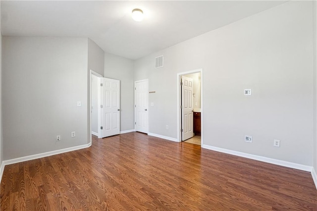 unfurnished bedroom featuring visible vents, connected bathroom, baseboards, and wood finished floors