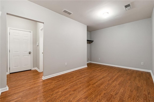 unfurnished room with wood finished floors, visible vents, and baseboards