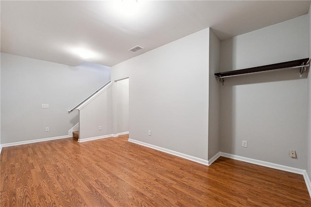 interior space with stairway, wood finished floors, visible vents, and baseboards