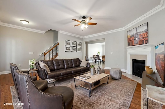 living room featuring stairs, baseboards, crown molding, and wood finished floors