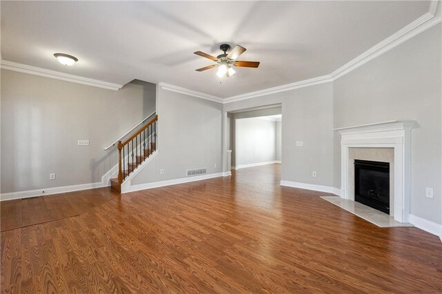 unfurnished living room featuring wood finished floors, visible vents, a high end fireplace, ornamental molding, and stairway