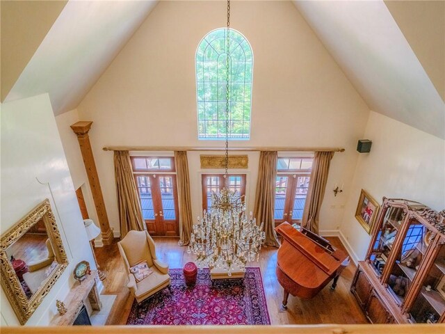 living room featuring high vaulted ceiling, an inviting chandelier, wood-type flooring, and french doors