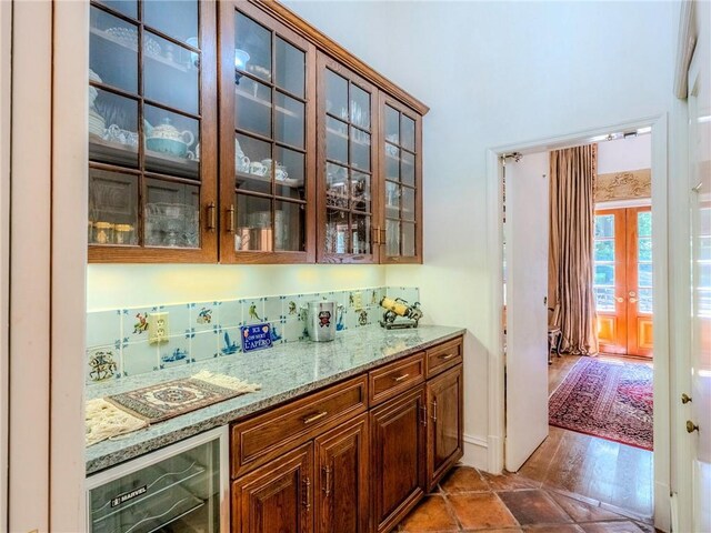 bar featuring light stone counters, beverage cooler, hardwood / wood-style floors, and tasteful backsplash