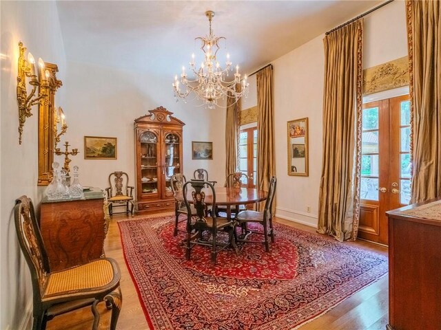 dining space featuring light hardwood / wood-style flooring, a notable chandelier, and french doors