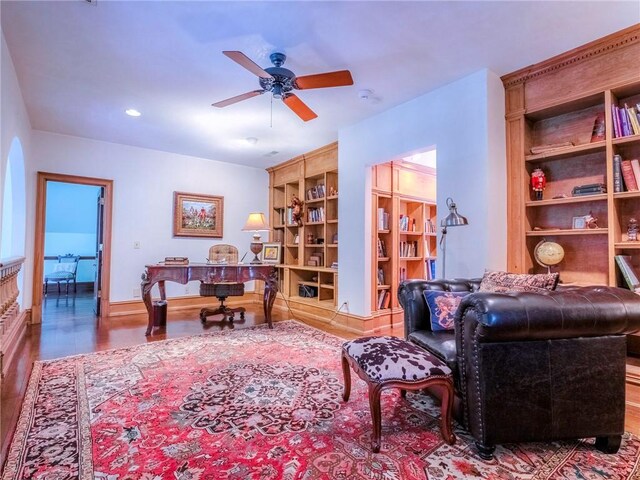 sitting room with built in shelves, ceiling fan, and wood-type flooring