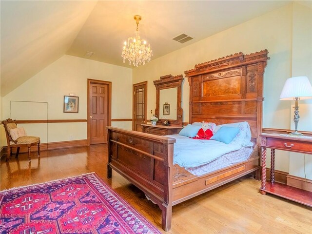 bedroom featuring vaulted ceiling, hardwood / wood-style flooring, and a notable chandelier