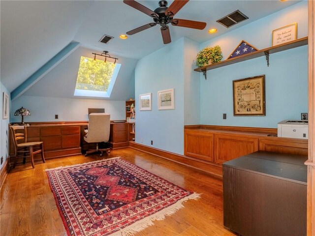 office area with light wood-type flooring, lofted ceiling, ceiling fan, and built in desk