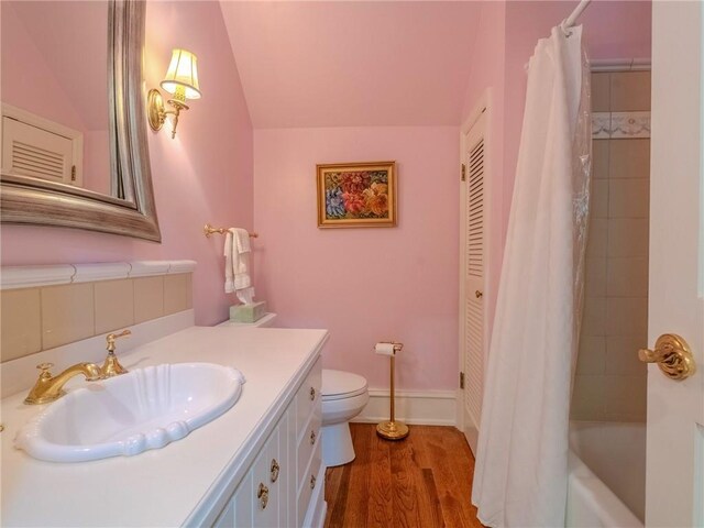 full bathroom with vanity, vaulted ceiling, shower / tub combo with curtain, wood-type flooring, and toilet