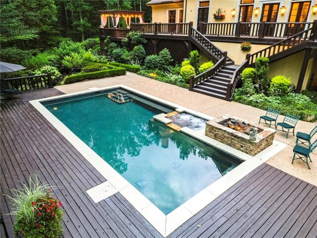 view of swimming pool with a deck and an outdoor fire pit