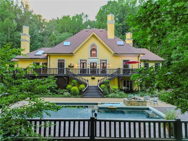 rear view of house featuring a patio and a pool with hot tub