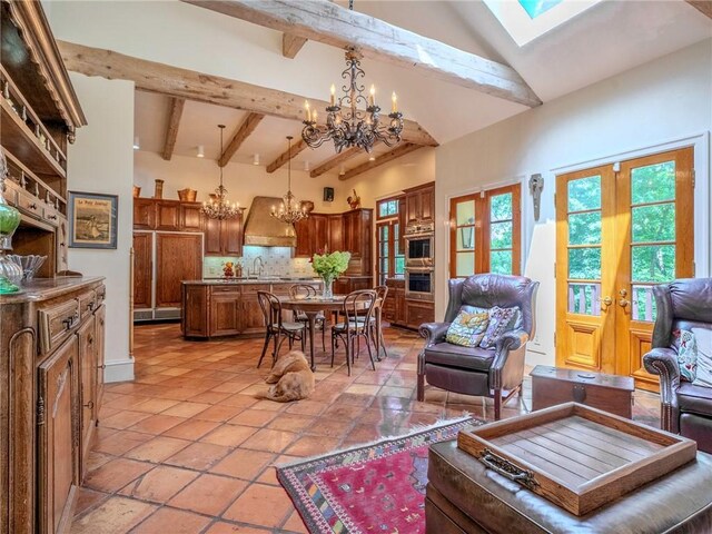 tiled living room featuring high vaulted ceiling, a skylight, beam ceiling, and a notable chandelier