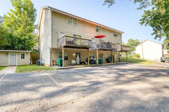 back of property featuring uncovered parking, a wooden deck, and central AC unit