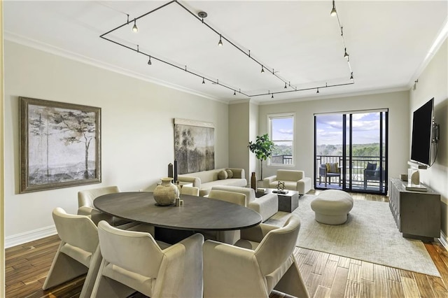 dining space featuring crown molding, rail lighting, wood finished floors, and baseboards