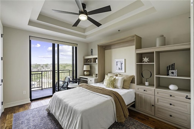 bedroom featuring a raised ceiling, access to outside, dark wood finished floors, baseboards, and ceiling fan