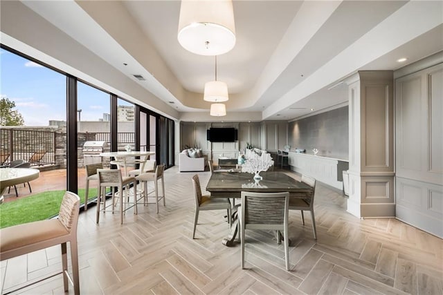 dining area with a raised ceiling and a decorative wall