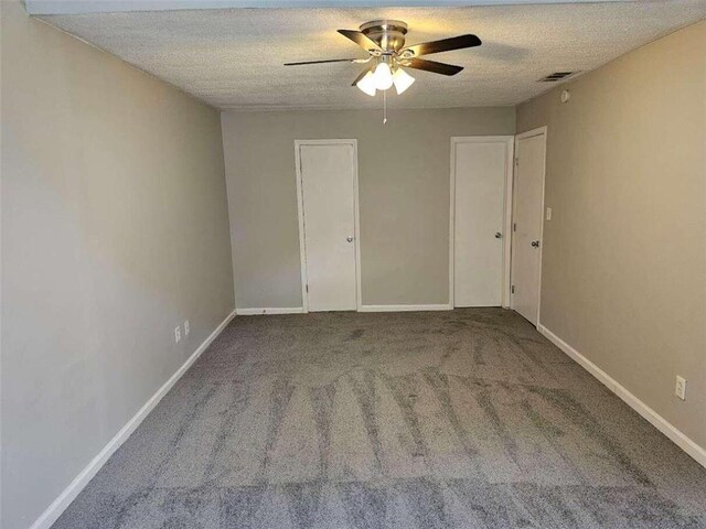 carpeted empty room featuring ceiling fan and a textured ceiling