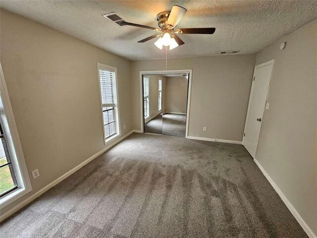 carpeted empty room featuring ceiling fan and a textured ceiling