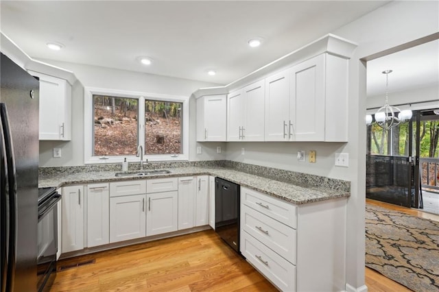 kitchen with light hardwood / wood-style floors, sink, white cabinets, and black appliances