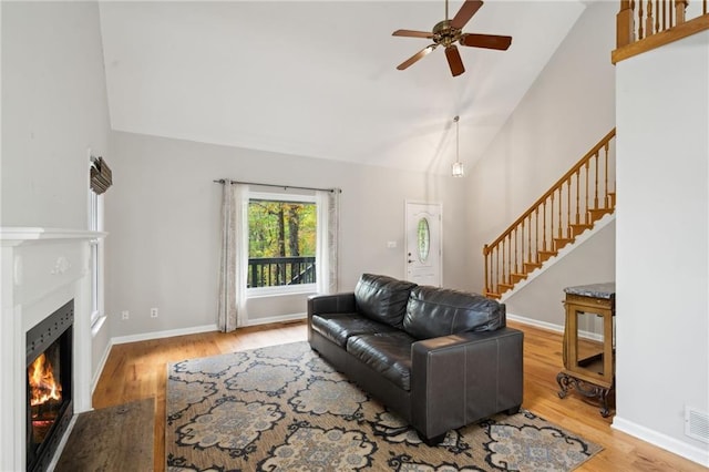 living room with ceiling fan, high vaulted ceiling, and wood-type flooring