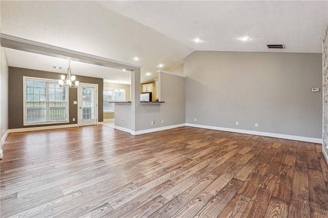 unfurnished living room featuring light hardwood / wood-style flooring, a chandelier, and vaulted ceiling