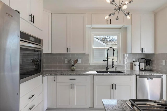 kitchen featuring backsplash, white cabinetry, stainless steel appliances, and a sink