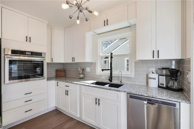 kitchen with tasteful backsplash, a sink, white cabinets, stainless steel appliances, and dark wood-style flooring