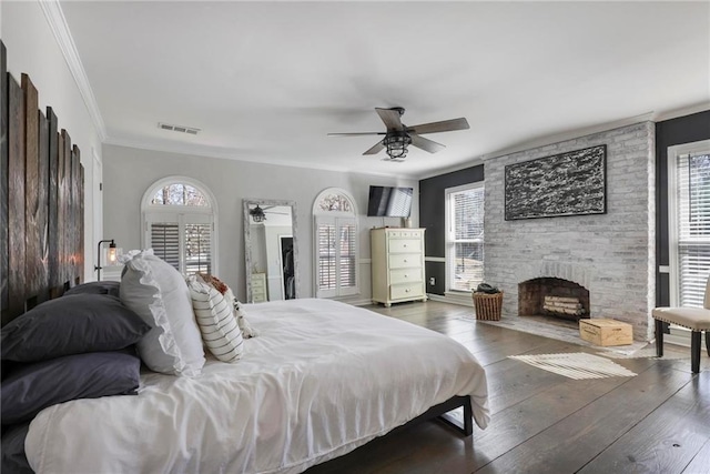 bedroom with visible vents, crown molding, ceiling fan, hardwood / wood-style floors, and a fireplace