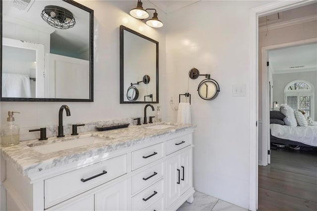 ensuite bathroom featuring a sink, connected bathroom, double vanity, and crown molding