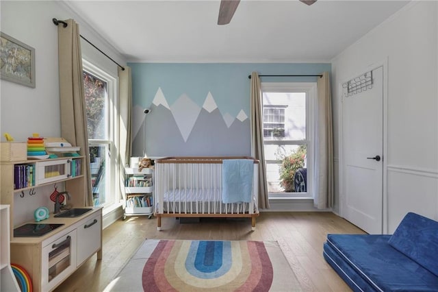 bedroom with crown molding, light wood-type flooring, ceiling fan, and a sink