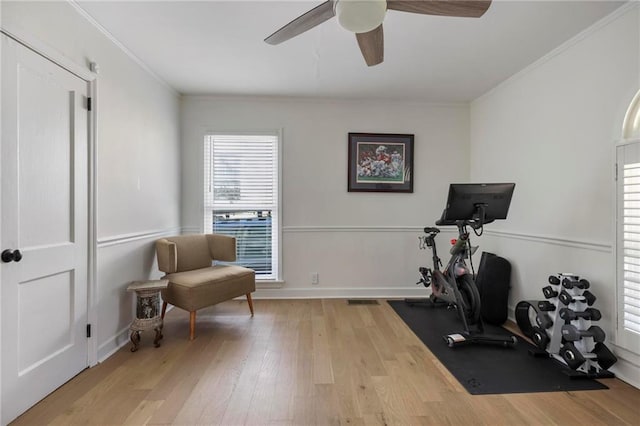 exercise room with a ceiling fan, wood finished floors, baseboards, and ornamental molding