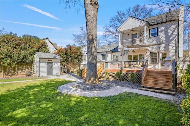 view of yard with a balcony, a ceiling fan, fence, a shed, and an outdoor structure