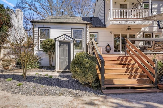 doorway to property with a balcony and roof with shingles