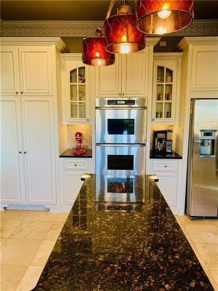 kitchen featuring stainless steel appliances, white cabinets, crown molding, decorative light fixtures, and light tile patterned floors